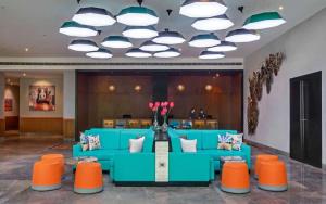 a lobby with a blue couch and orange chairs at Triton By Shyama Hotels & Resorts in Raipur