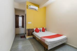 a bedroom with a bed with red pillows at OYO Supriya Lodge in Hassan