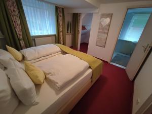Schlafzimmer mit einem Bett mit weißer Bettwäsche und gelben Kissen in der Unterkunft Room in BB - Pension Forelle - Doppelzimmer in Forbach