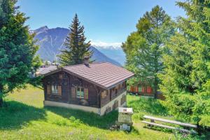 uma pequena casa numa colina com montanhas ao fundo em Chalet Leiggener em Rosswald