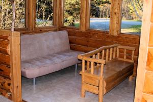 eine Bank und ein Stuhl in einem Zimmer mit Fenstern in der Unterkunft Bear Den Vacation Home in Anchor Point