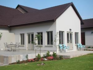 Casa blanca con sillas azules y patio en Bergliot Guest House en Edenvale