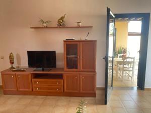 a living room with a television on a wooden cabinet at Casa Isabel in La Oliva