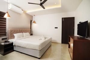 a bedroom with a bed and a flat screen tv at 7 The Business Hotel in Alwaye +16 photos