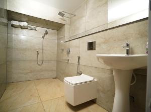 a bathroom with a toilet and a sink and a shower at 7 The Business Hotel in Alwaye