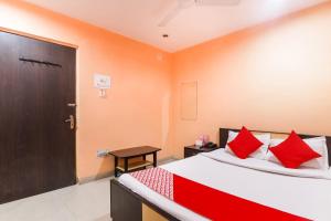 a bedroom with a bed with red pillows and a door at Hotel Priyal in Chās