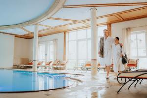 Ein Mann und eine Frau stehen neben einem Schwimmbad in der Unterkunft Hotel Dirsch Wellness & Spa Resort in Emsing