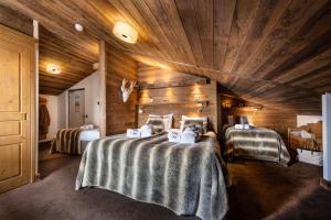 a bedroom with two beds and a wooden ceiling at Hôtel Ski Lodge - Village Montana in Val dʼIsère