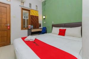 a bedroom with a bed with a red blanket on it at OYO 91292 Pondok Inap Shofwa 1 in Sidoarjo