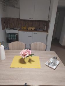 eine rosa Rose auf einer gelben Serviette auf einem Tisch in der Unterkunft Kolpingház Pécs in Pécs