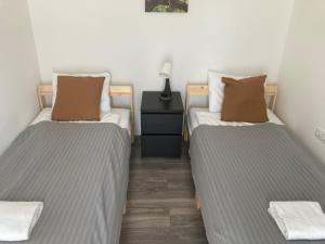 two twin beds in a room with a night stand at Hód-Thermal Camping in Hódmezővásárhely