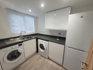 una cocina blanca con lavadora y secadora. en Midland Close Bungalow - With separate office space by Catchpole Stays, en Colchester