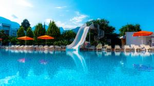 a slide in a swimming pool with chairs and umbrellas at OMORFİ GARDEN RESORT in Dedeköy