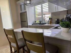 a kitchen with a white counter and two chairs at 2 Units, 1 Price Group Bundle Sleeps 8 Beach House in Luquillo