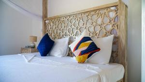 Schlafzimmer mit einem Bett mit weißer Bettwäsche und Kissen in der Unterkunft Relaxing Beach Front Villa in Mambrui