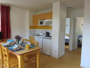 - une cuisine et une salle à manger avec une table et des chaises dans l'établissement Résidence Goélia Les Demeures du Lac, à Casteljaloux
