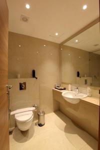 a bathroom with a toilet and a sink and a mirror at National Park residency in Ettumānūr