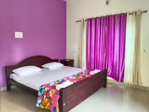 a bedroom with purple walls and a bed with a bedspread at Bliss on the Bay in Varkala