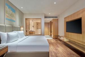 a bedroom with a large bed and a flat screen tv at Doubletree By Hilton Varanasi in Varanasi