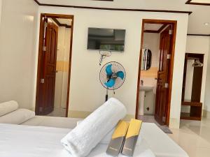 ein Schlafzimmer mit einem Bett, einem Ventilator und einem Buch in der Unterkunft Alocasia El Nido in El Nido