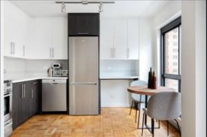 a white kitchen with a table and a refrigerator at Comfortable 3 Bedroom Apartment in New York
