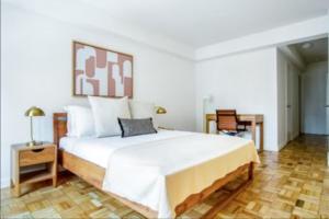 a bedroom with a large white bed and a table at Comfortable 3 Bedroom Apartment in New York