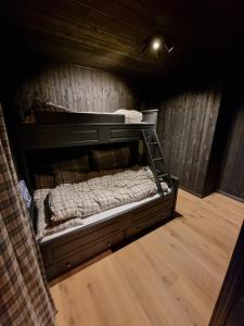 a bed in a room with a wooden wall at Kikut Alpin Lodge - Ski in, Ski out in Geilo