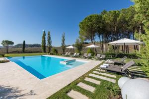 a swimming pool in a yard with chairs and an umbrella at PODERE BELLARIA 18&2, Emma Villas in Rapolano Terme