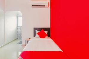 a bedroom with a red wall next to a bed at Flagship Hotel Maruthi Gandhi Park in Coimbatore