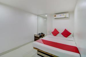 a small bedroom with a bed with red pillows at OYO Hotel Blue Light Near Gateway Of India Mumbai in Mumbai