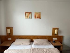 2 camas en un dormitorio con 2 lámparas en la pared en Brauhaus Hotel Ruetershoff, en Castrop-Rauxel