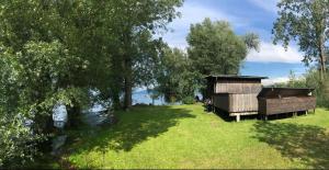 a wooden structure in the grass next to a river at Bodensee Wohnung 3 mit Privatstrand in Gaißau
