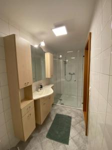 La salle de bains est pourvue d'un lavabo, d'une douche et d'une baignoire. dans l'établissement Bodensee Wohnung 2 mit Privatstrand, à Gaißau