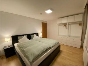 a bedroom with a large bed with white walls at Bodensee Wohnung 2 mit Privatstrand in Gaißau