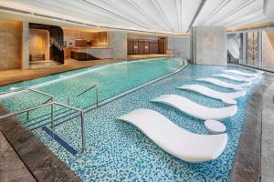 a swimming pool with a row of white chairs at Studio City - Epic Tower in Macau