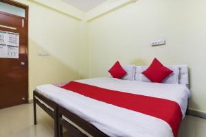 OYO Ruby Grand Inn في Kondapur: سرير مع وسائد حمراء في الغرفة