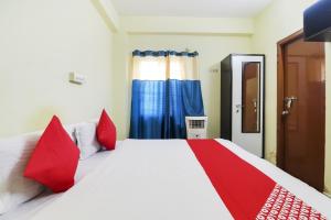 OYO Ruby Grand Inn في Kondapur: غرفة نوم مع سرير أبيض كبير مع وسائد حمراء