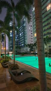 a swimming pool at night with palm trees and buildings at The New Villa at Sea Residences in Manila