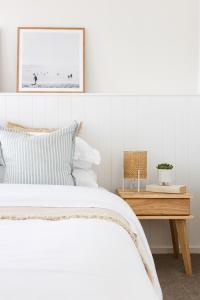a white bedroom with a bed and a wooden table at Rosebay - Coastal Holiday Home in Rosebud