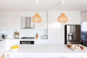 a white kitchen with a refrigerator and a bowl of fruit at Rosebay - Coastal Holiday Home in Rosebud