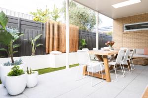 a patio with a wooden table and chairs and plants at Rosebay - Coastal Holiday Home in Rosebud