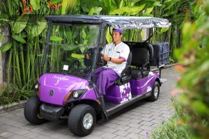 mężczyzna siedzący w wózku golfowym w obiekcie Amadea Resort & Villas Seminyak Bali w mieście Seminyak