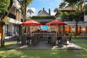 a patio with a bar with chairs and umbrellas at Amadea Resort & Villas Seminyak Bali in Seminyak