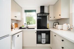 a kitchen with white cabinets and a black stove top oven at Rural escape with peaks from your door in Sheffield