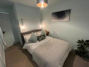 a bedroom with a white bed with pillows on it at The Coachhouse, Hot Tub in Henley in Arden