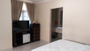 a bedroom with a bed and a flat screen tv at Grand Melka Hotel in Lovina