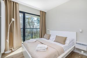 a bedroom with a large bed with a window at Shellter Apartments 117 H - by Jantar Apartamenty in Rogowo