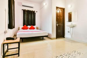 a bedroom with a bed with red pillows and a sink at OYO Flagship Ag Colony in Patna