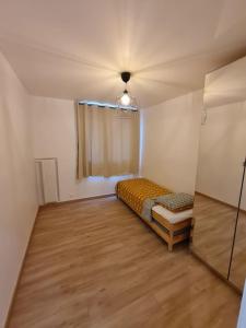 um pequeno quarto com uma cama e uma janela em Appartement Spacieux et Rénové em Neuilly-sur-Marne