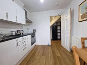 een keuken met witte kasten en een houten vloer bij Nice Living Serviced Accommodations 9 (King-Size Studio Flat + Kitchen) in Coventry